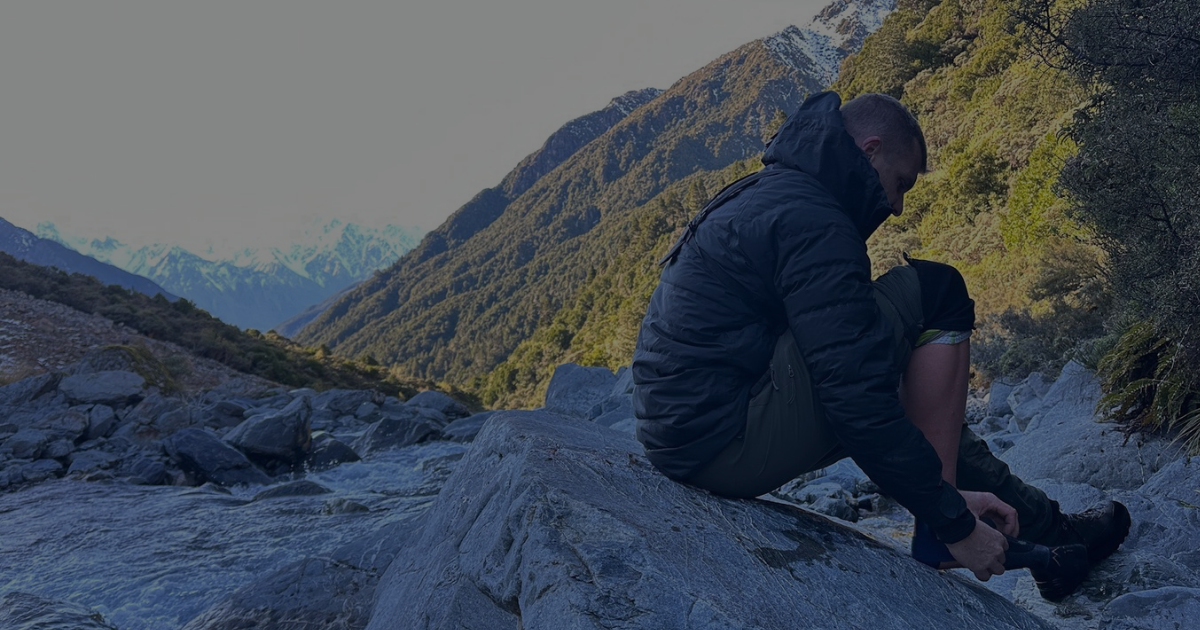 Person sitting beside a mountain stream in the Southern Alps, New Zealand.