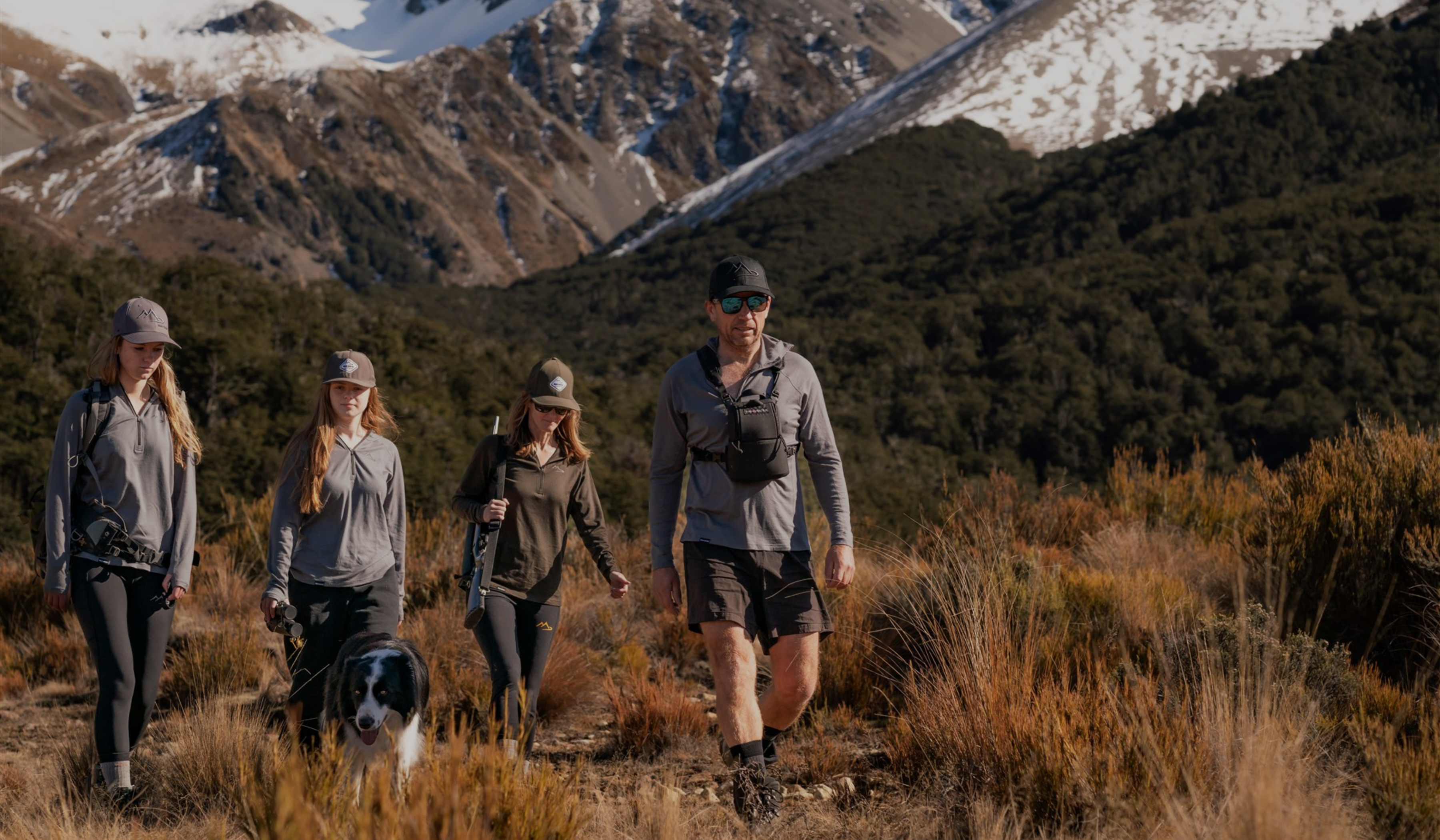 Main Divide Apparel team hiking in NZ high country with outdoor gear and dog